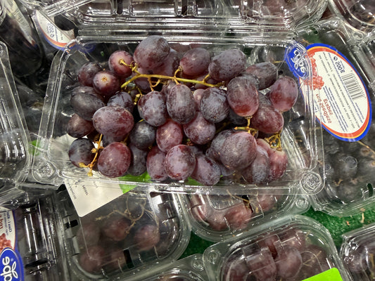 Plastic container of purple grapes with a visible brand label.